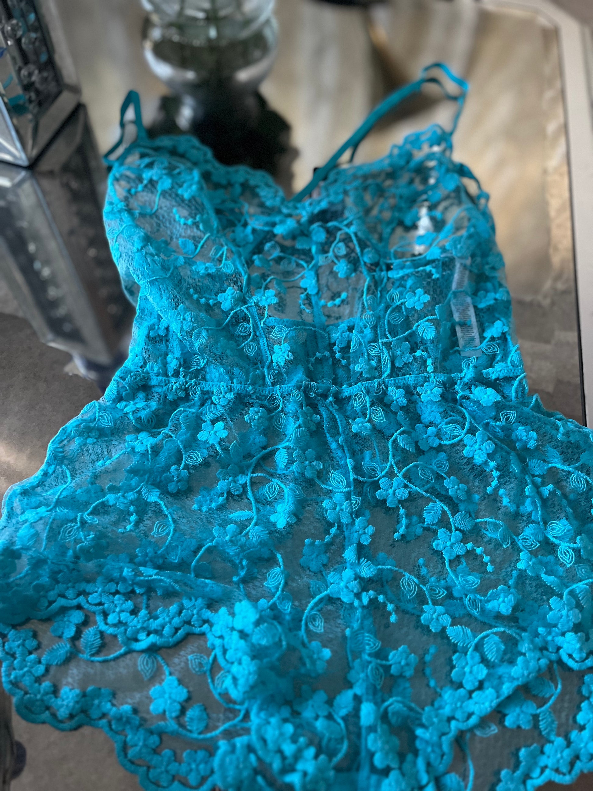 Close up of embroidered floral lace on turquoise sleep romper